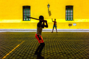 Cuba, Havanna, two boys playing Stick Ball in front of a yellow wall Cuba, Havanna, two boys playing Stick Ball in front of a yellow wall